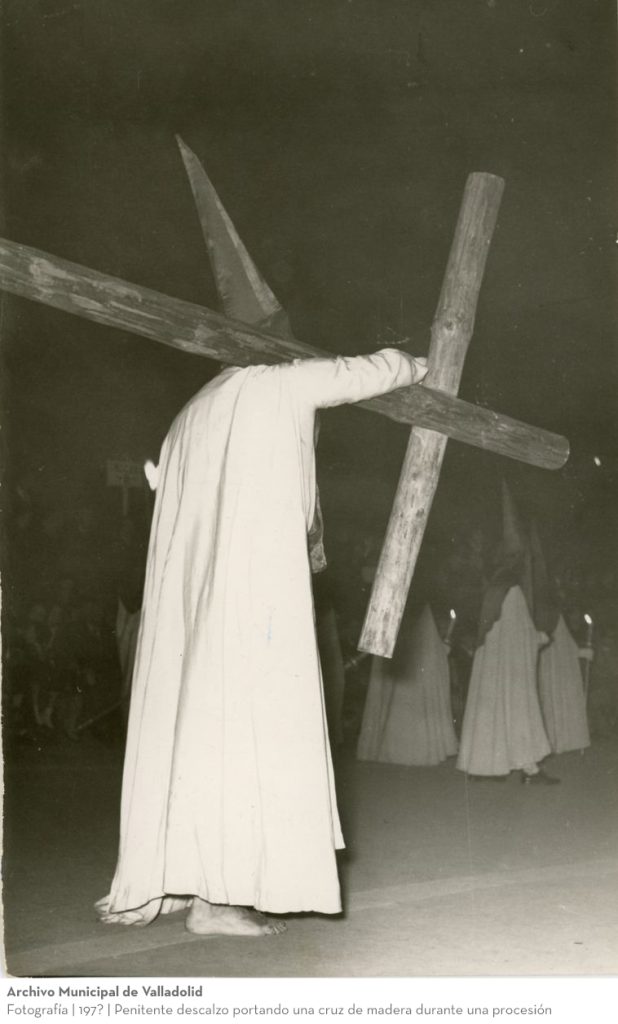 Fotografía. 197? Penitente descalzo portando una cruz de madera durante una procesión